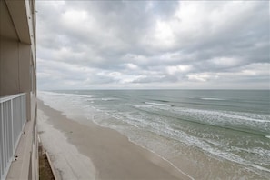 A beach view with waves and overcast sky.