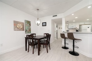 A modern kitchen with white cabinets, a central island, and bar stools.
