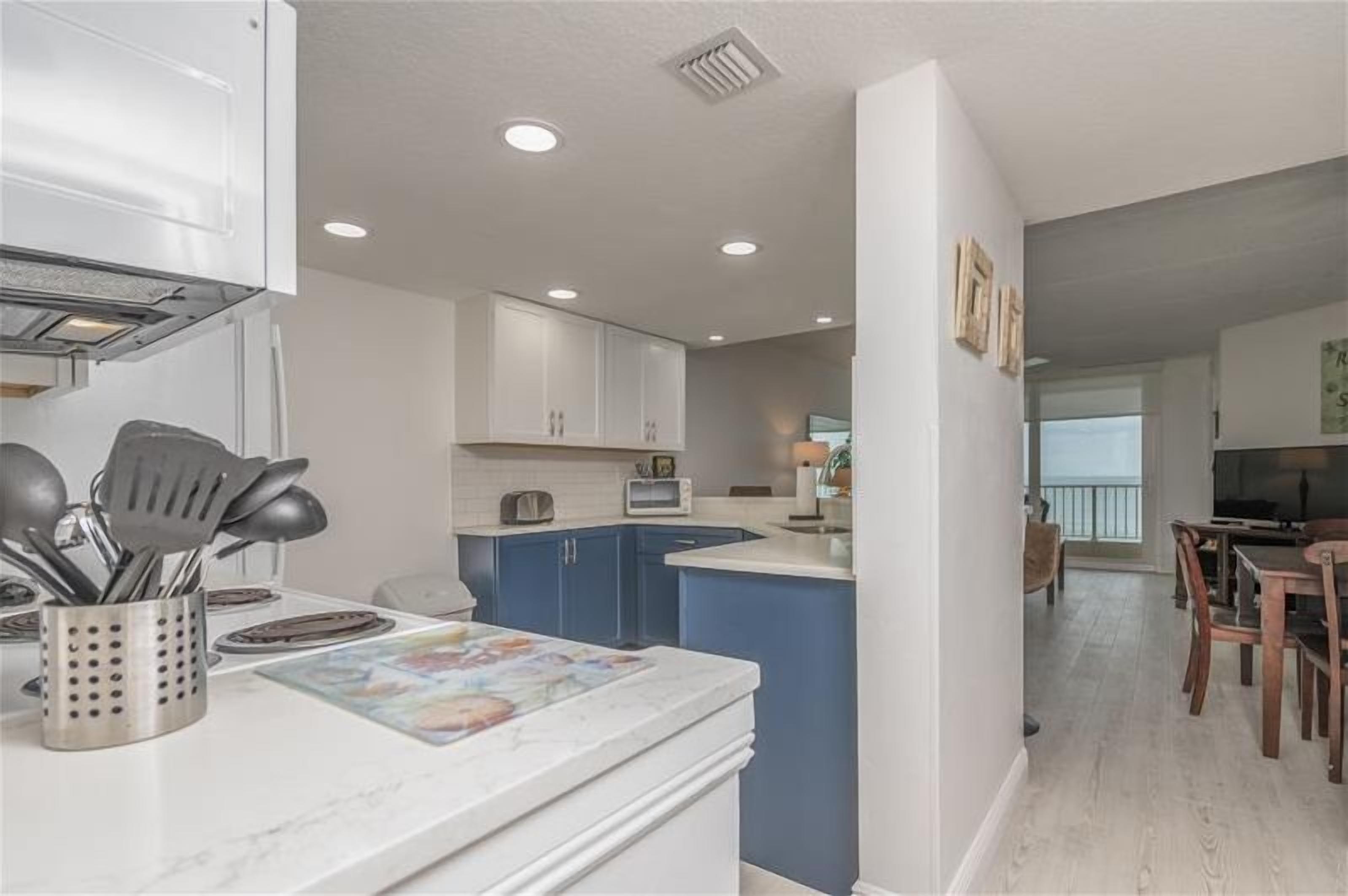 Una cocina moderna con armarios blancos, detalles azules y una isla central.
