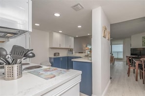 A modern kitchen with white cabinets, blue accents, and a central island.