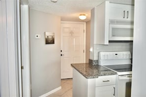 A kitchen with white cabinets, a built-in oven, and a granite countertop.