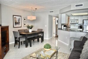 A modern living room with a dining area, a kitchen, and a seating area.