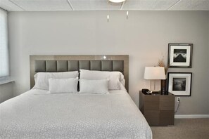 A neatly made bed with a headboard, a bedside table with a lamp, and two framed pictures on the wall. - Perfect Location in Ponce Inlet for this 2/2 oceanfront Condo 504 South Point (Ponce Inlet)