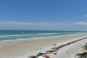 A beach with a clear sky, a sandy shore, and a few umbrellas. - #504 Southpoint 2/2 Oceanfront Traffic Free Beach (Ponce Inlet)