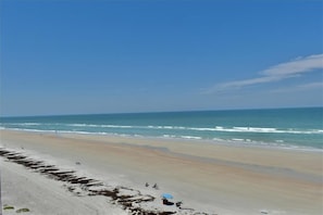 A beach with a clear sky, calm sea, and a sandy shore.