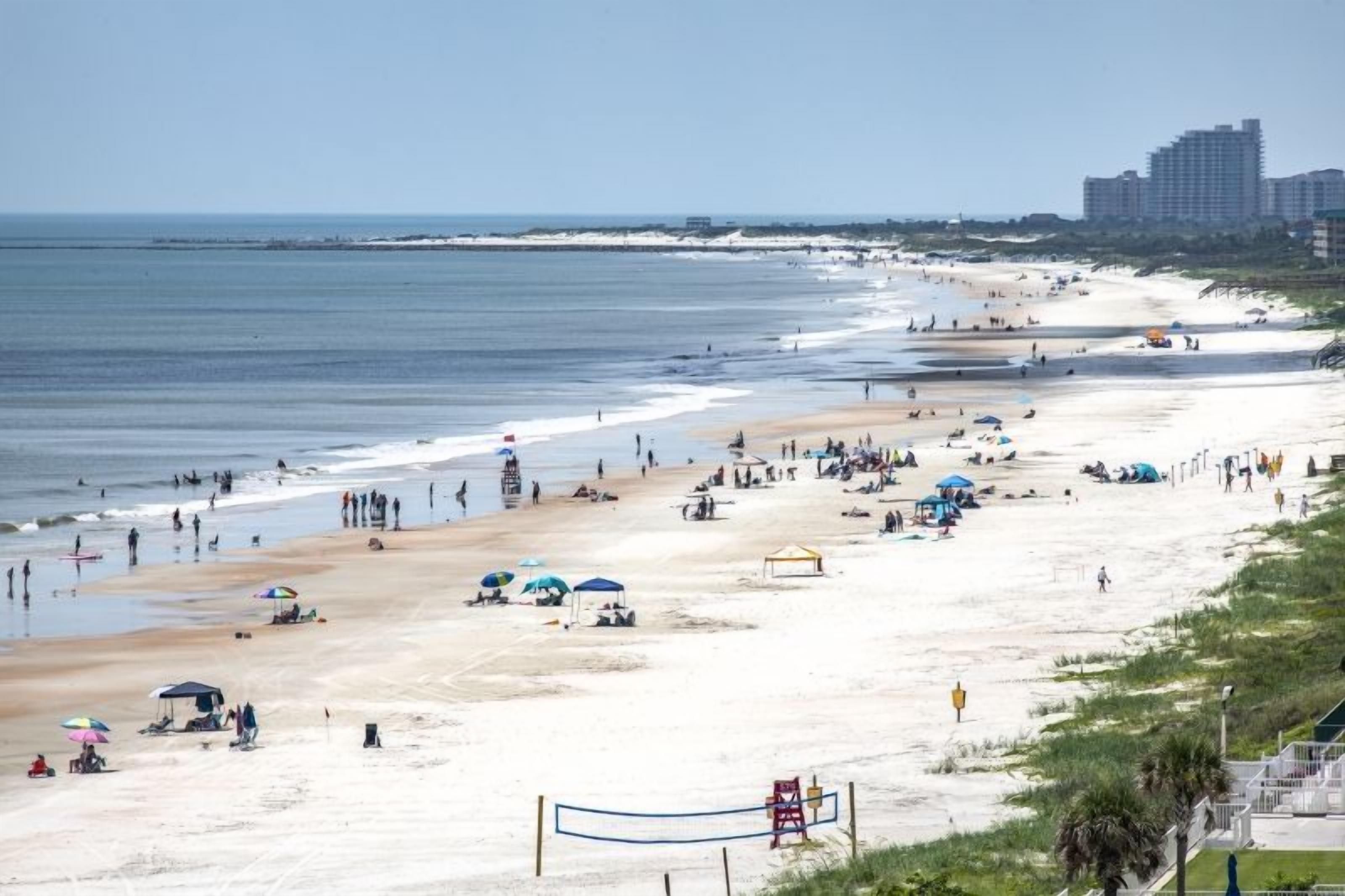 Een strand met mensen, parasols en een uitkijktoren.