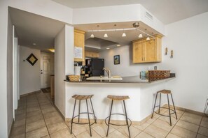 A kitchen with a central island, bar stools, and a refrigerator. - 7th Floor Unit 709 Oceanfront with Great Views in Ponce Inlet (Ponce Inlet)