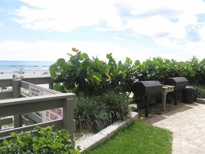 A patio area with a view of the beach, a sign indicating 'Please keep off sand', and barbecue grills. - 7th Floor Unit 709 Oceanfront with Great Views in Ponce Inlet (Ponce Inlet)