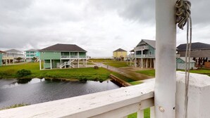 A waterfront property with multiple houses, a small bridge, and a grassy area. - A Wave From Everything (Bolivar Peninsula)