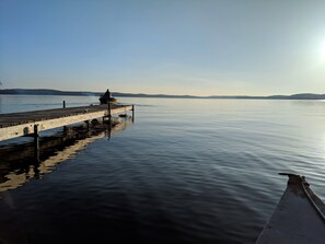 A wooden pier extending into calm water with a person sitting at the end. - Luxury Glamping w/Resort Access Included, Site 3 (Phelps)
