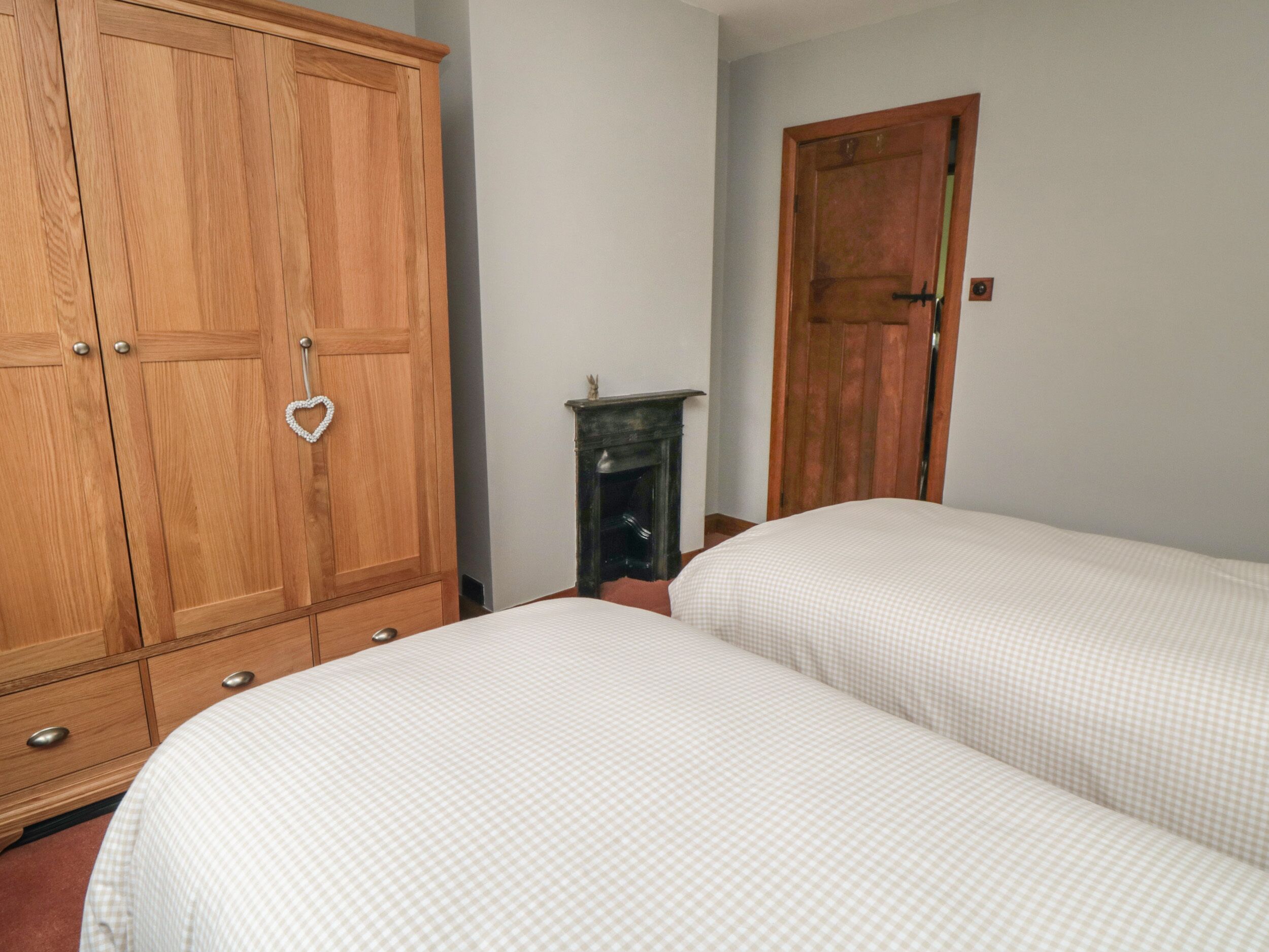 A bedroom with two beds, wooden wardrobe, and a small fireplace.