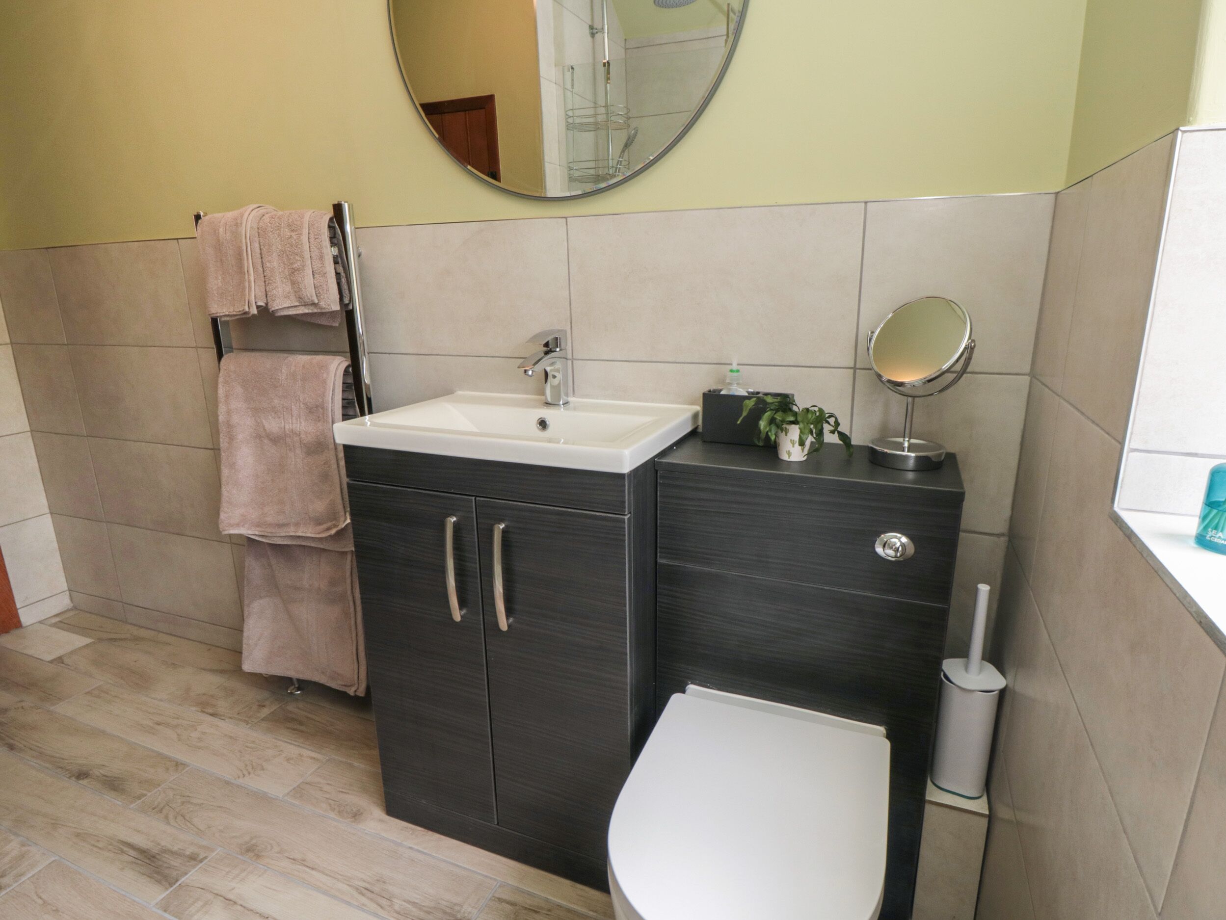 Een badkamer met een wastafel, spiegel, toilet en handdoekhouder.