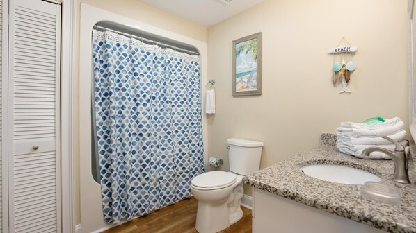 Un baño con cortina de ducha, inodoro, lavabo y un toallero con toallas.