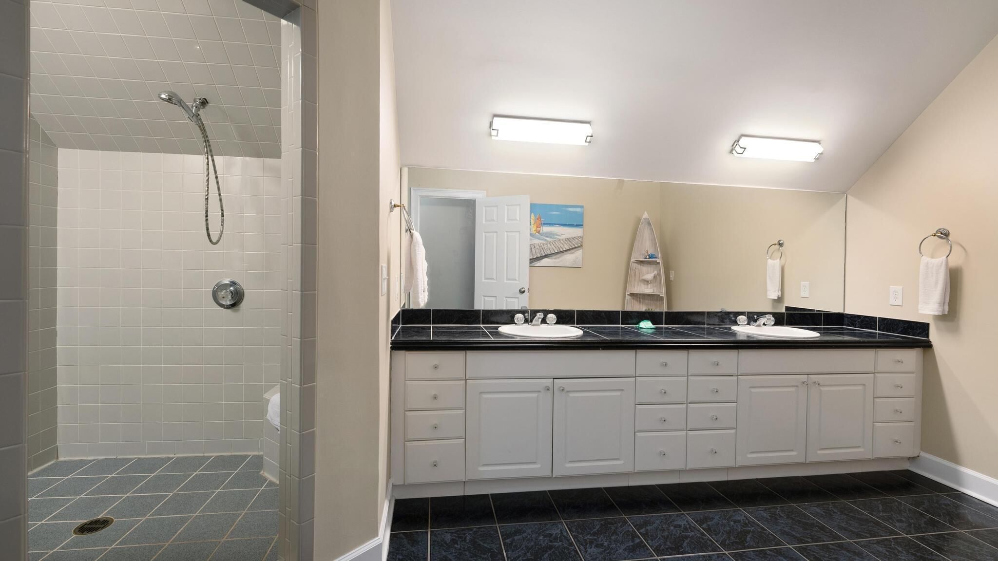 A modern bathroom with a walk-in shower, two sinks, and a large mirror.