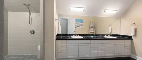 A modern bathroom with a walk-in shower, two sinks, and a large mirror.