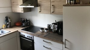Cocina moderna con armarios de madera, campana de acero inoxidable, horno integrado, cafetera y hervidor.