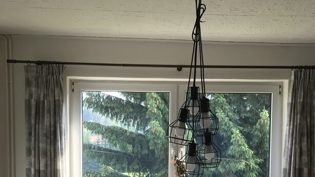 Un comedor con una mesa, sillas, un radio y vista a un bosque a través de amplios ventanales.