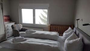 Un dormitorio con dos camas, una ventana, una cuna y un aparador.