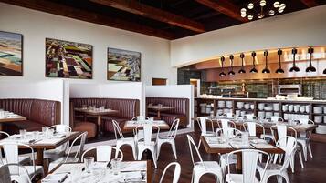 Un restaurant amb seients tipus boxa i taules, bigues de fusta al sostre i llums penjants.
