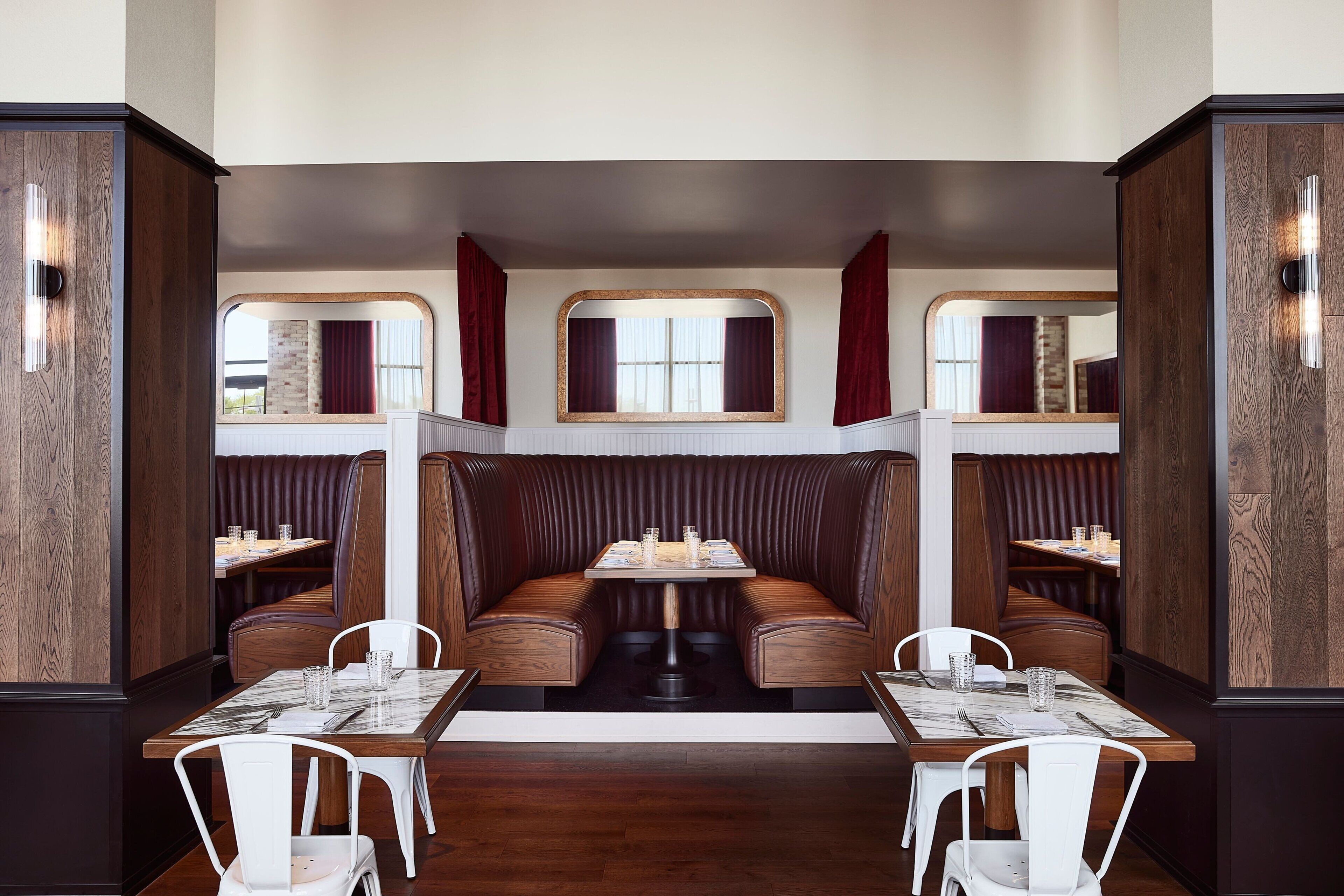 A restaurant with booth seating, a central table, and a mirrored wall.