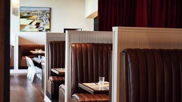 A restaurant with booth seating, a dining area, and a painting on the wall.