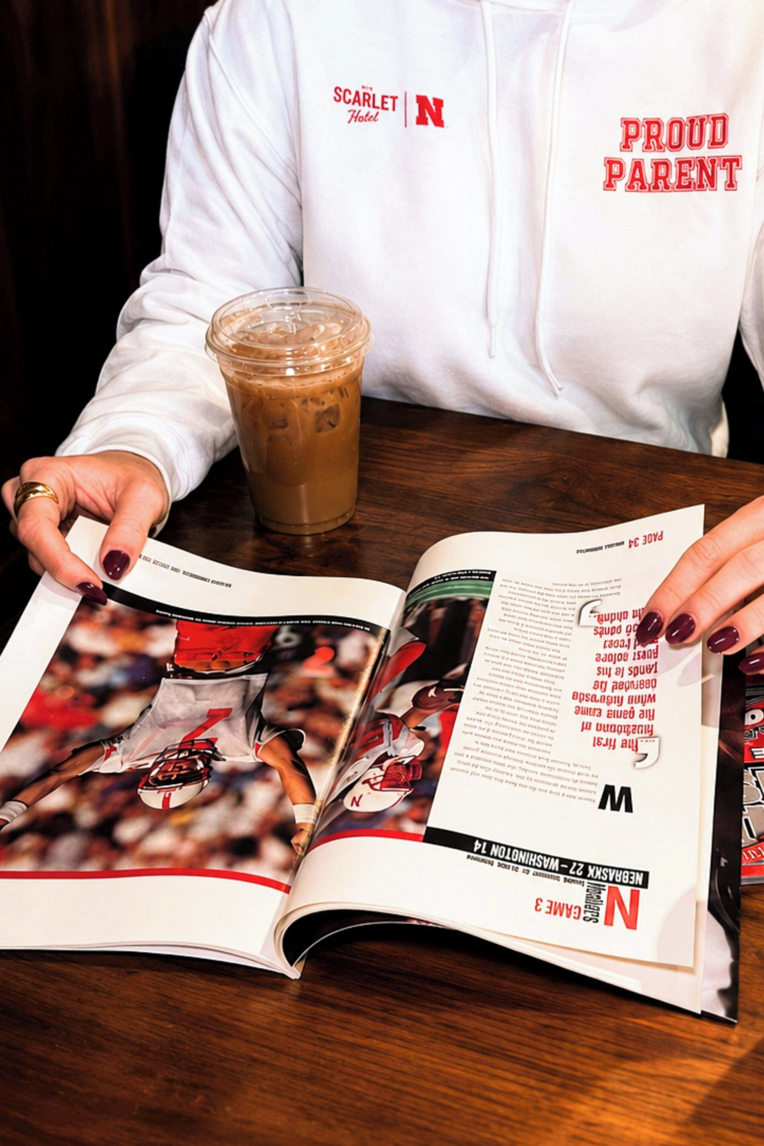 A person reading a magazine with a coffee cup on a table.