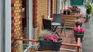 Ein Backsteinhaus mit einem Balkon, der Sitzgelegenheiten und Blumentöpfe im Freien bietet.