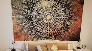 Ein Schlafzimmer mit Bett, Nachttischen und einer großen Wanddekoration.