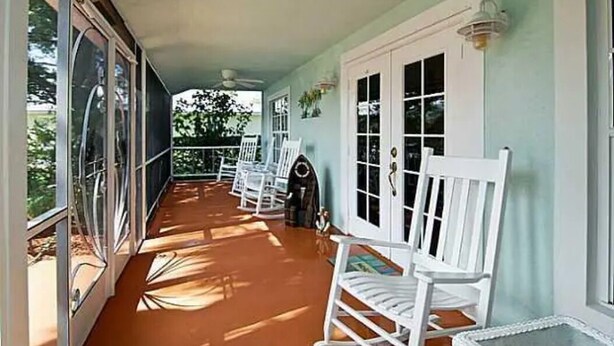 Eine überdachte Veranda mit weißen Schaukelstühlen und einem kleinen Tisch.