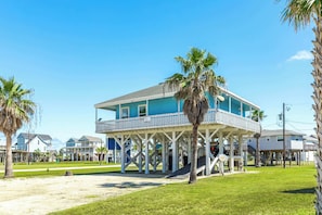Une maison située en bord de mer, dotée d’un balcon, de palmiers et surplombant un ciel dégagé.