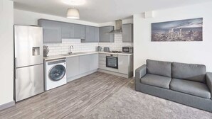 Una cocina moderna con armarios grises, una lavadora y un sofá gris en la sala de estar.