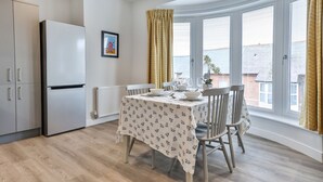 Una cucina moderna con frigorifero integrato, un tavolo da pranzo con sedie e ampie finestre vista mare.