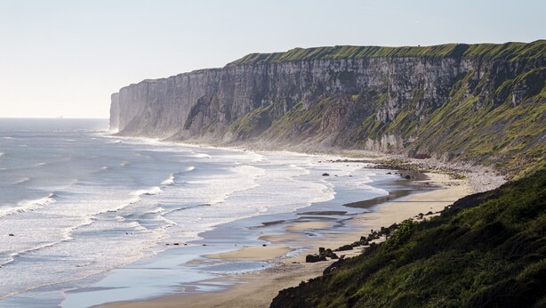 Paesaggio costiero con scogliere e una spiaggia.