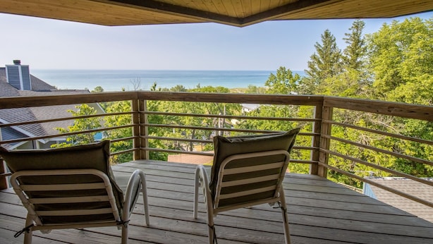 A wooden deck with two chairs facing a scenic ocean view. - Big Hilltop Home with Gorgeous Lake Views & Beach Access (Michigan City)