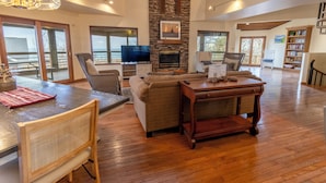 A spacious living area with a fireplace, a television, and a bookshelf. - Big Hilltop Home with Gorgeous Lake Views & Beach Access (Michigan City)