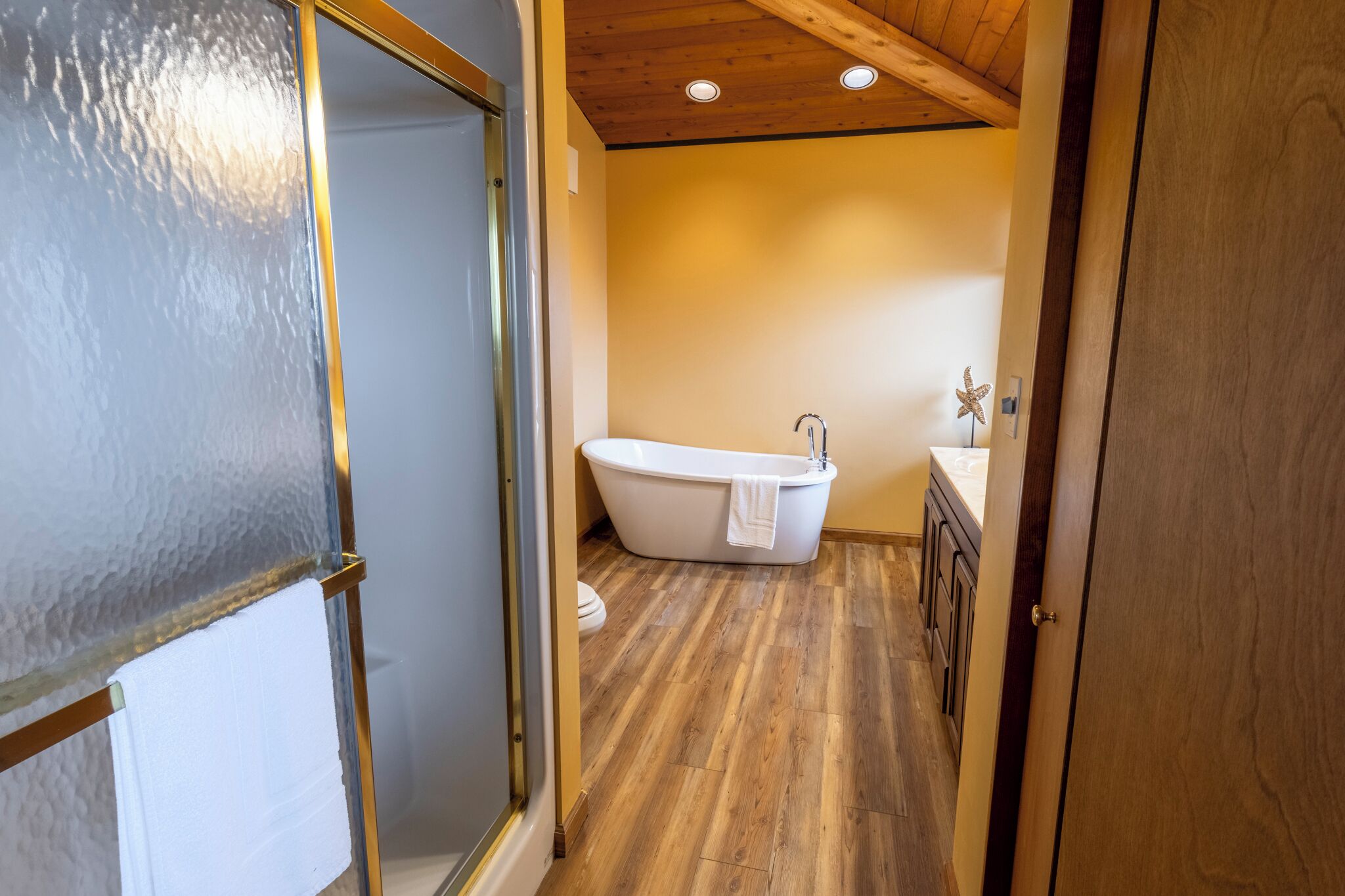 A bathroom with a freestanding bathtub, wooden flooring, and a starfish decoration on the wall.