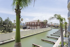 Vista de un canal con muelles, un edificio de fachada roja y palmeras.