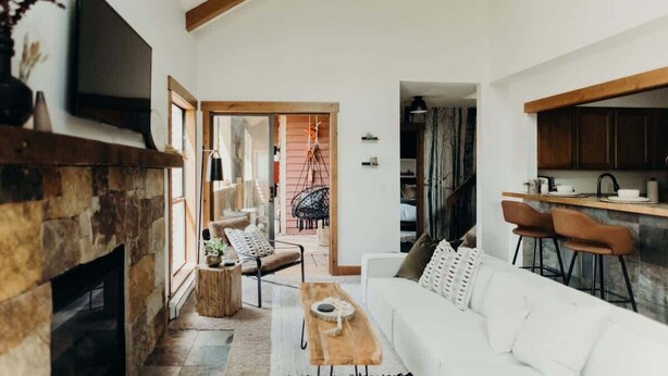 A living room with a fireplace, a sofa, a coffee table, and a television mounted on the wall. - Prime Location | Luxurious Condo | Near Main St (Breckenridge)