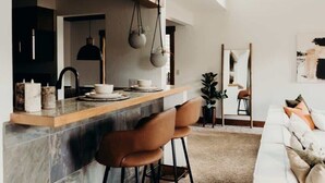 A modern kitchen with a marble countertop, two bar stools, and pendant lighting. - Prime Location | Luxurious Condo | Near Main St (Breckenridge)