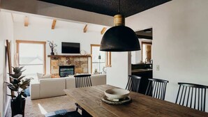A modern living room with a fireplace, a dining table, and a large pendant light. - Prime Location | Luxurious Condo | Near Main St (Breckenridge)
