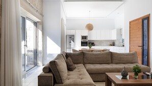 A modern living room with a sectional sofa, a coffee table, and a view of the kitchen and dining area. - Mandana Villa - With Private Pool & Jacuzzi (Pigi)