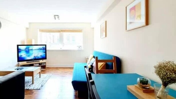 A living room with a television, sofa, and a window.