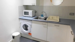 A compact kitchen with a microwave, sink, and washing machine.