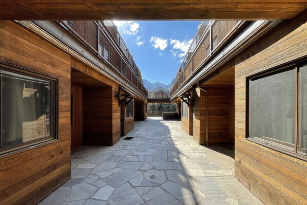 A corridor with wooden walls and large windows, leading to a mountain view.