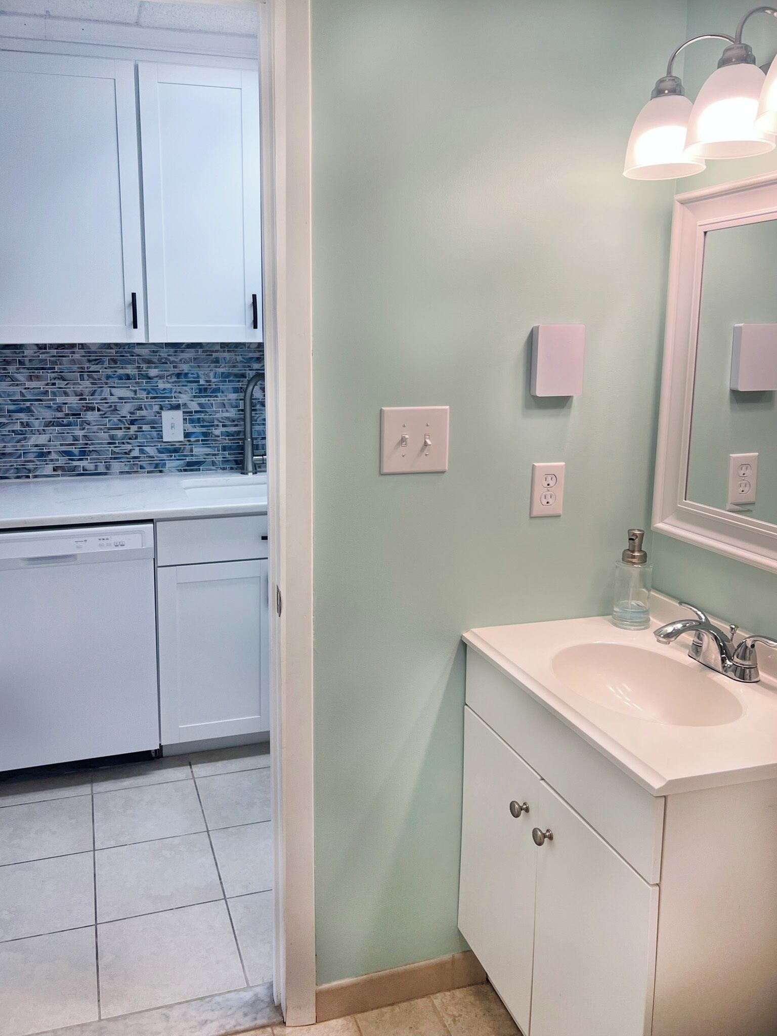 A modern bathroom with a sink, mirror, and light fixture.