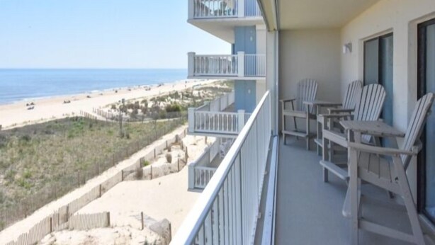 A balcony with white chairs and a view of the beach. - Direct ocean front  * 2 Bedrooms * 2 Full Baths + Den * 4th Floor Sleeps 8 * (Ocean City)