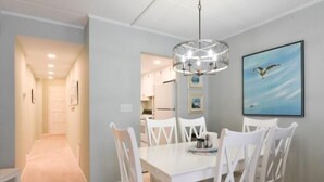 A dining area with a white table and chairs, a chandelier, and a framed picture on the wall. - Direct ocean front  * 2 Bedrooms * 2 Full Baths + Den * 4th Floor Sleeps 8 * (Ocean City)