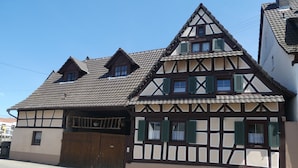 A traditional half-timbered house with a steeply pitched roof, a wooden gate, and a small balcony. - s Moose Hof (Weisweil)