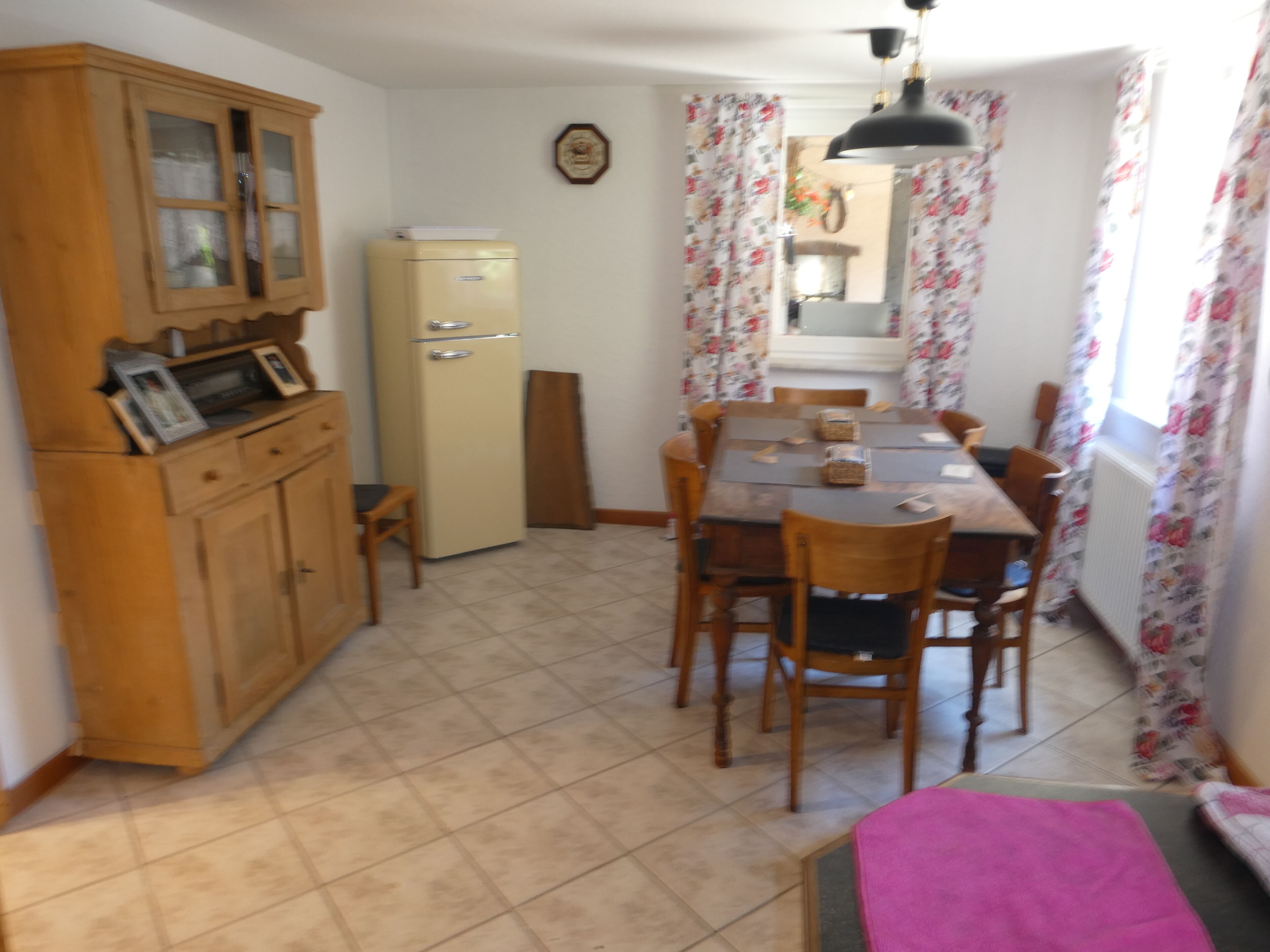 Une cuisine compacte comprenant un coin repas, des meubles de rangement en bois, un réfrigérateur et une table à manger avec des chaises.