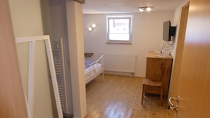 A room with a bunk bed, a desk with a chair, a radiator, and a window. - s Moose Hof (Weisweil)